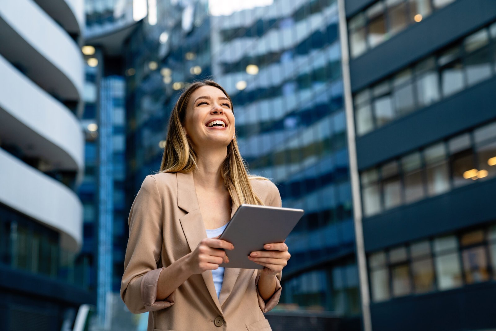 Portrait of a successful young business woman using digital tablet in front of modern business building
